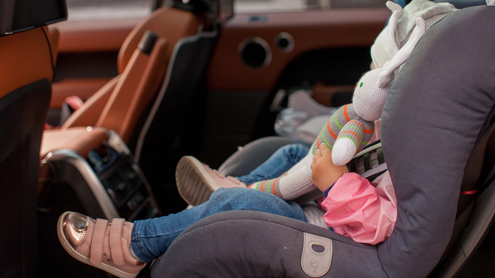 Year-old Baby Buckled into her Car seat, Girl Travels in Car with Parents looking out the Window at sunset - Image